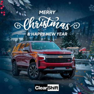 Red Chevrolet Suburban driving on a snowy mountain highway, with Merry Christmas message.